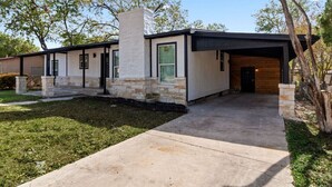 A modern two-story house with a stone facade, large windows, and a covered driveway.