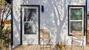 A modern building with a wooden deck, a door, and two windows.
