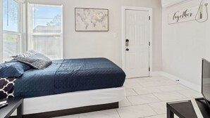 A bedroom with a bed, a ceiling fan, a world map on the wall, a door, and a sign that says "Together".