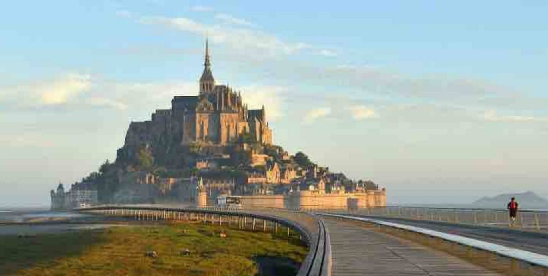 A large, historic castle-like structure with a prominent tower, situated on a hill overlooking a body of water.