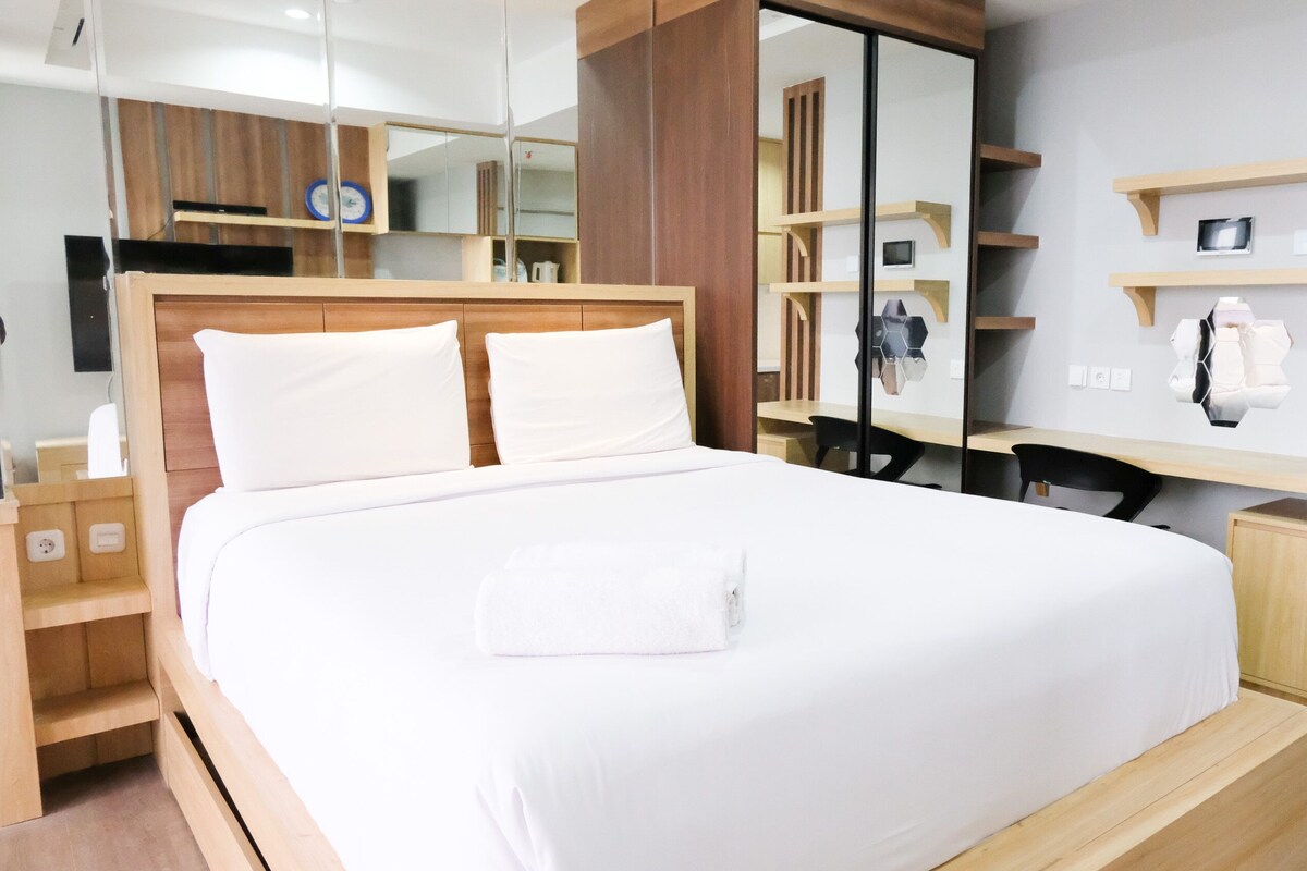 A modern hotel room with a large bed, wooden headboard, and built-in wooden shelves.