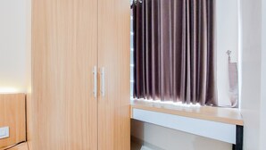 A room with a wooden wardrobe, a window with curtains, and a desk. - Minimalist Studio Apartment At Serpong Garden (Cisauk)