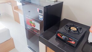 A compact kitchen with a black refrigerator, a gas stove, and a small countertop. - Minimalist Studio Apartment At Serpong Garden (Cisauk)