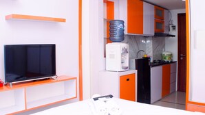 Habitación de hotel pequeña con televisión, kitchenette y cama.