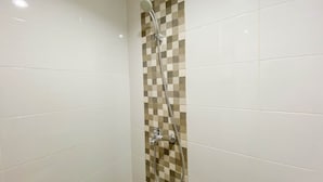 A shower with a checkered tile wall and a chrome showerhead. - Fully Furnished 1Br The Alton Apartment (Semarang)