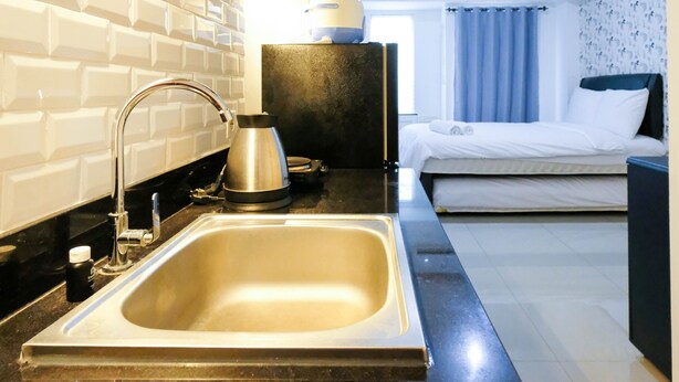 A modern hotel bathroom with a large sink, a kettle, and a small table. - Clean Studio With Connected To Mall At Orchard Supermall Mansion Apartment (Surabaya)