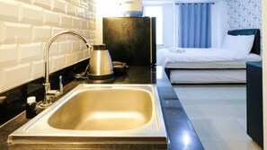 A modern hotel bathroom with a large sink, a kettle, and a small table. - Clean Studio With Connected To Mall At Orchard Supermall Mansion Apartment (Surabaya)