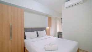 A hotel room with a bed, wooden wardrobe, and an air conditioning unit.