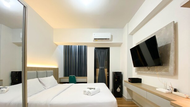 Habitación de hotel con una cama grande, un escritorio, un televisor de pantalla plana en la pared y una cafetera.