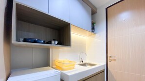 Una kitchenette compacta con un refrigerador blanco, un lavamanos y una repisa sobre la encimera.