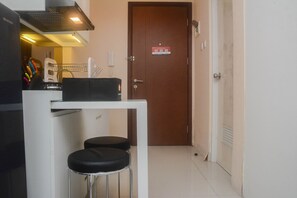 Compact kitchen area with a toaster and a rice cooker, featuring a tiled floor and a door leading to another room.
