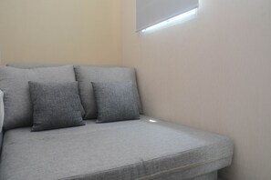 Relax in comfort on the plush sofa, positioned beside a window with a view.