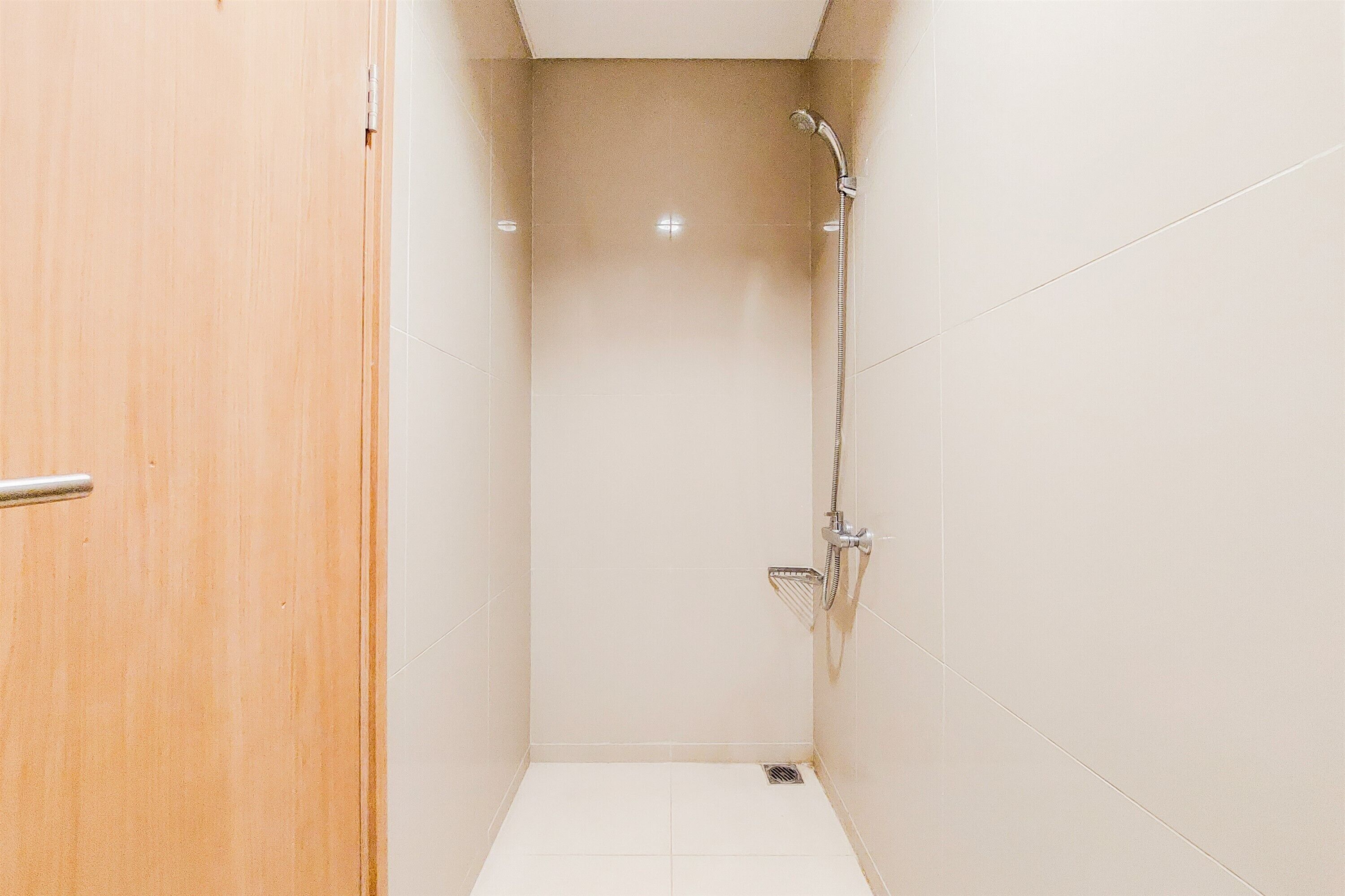 A small, enclosed shower area with a showerhead and a handheld shower attachment.
