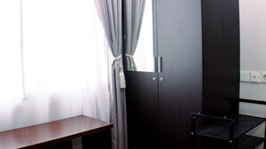 A room with a wooden desk, a dark wardrobe, and a black shelving unit. - Comfort Studio At Marina Ancol Apartment (Jakarta)