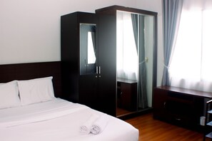 A hotel room with a bed, a wardrobe, a mirror, and a desk.