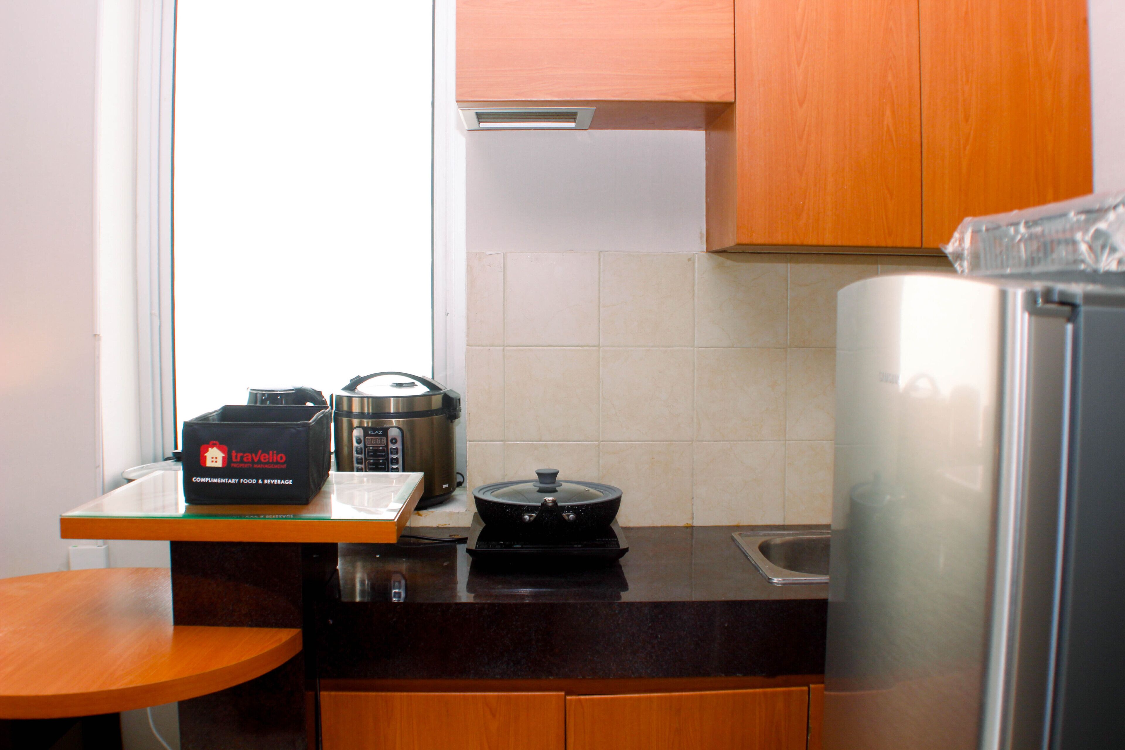 A kitchen with a countertop, a stove, a slow cooker, a sink, and wooden cabinets.