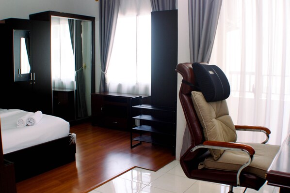 A hotel room with a bed, a desk, a chair, and a wardrobe.