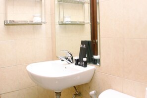 A bathroom with a white sink, a mirror, and two shelves above the sink.