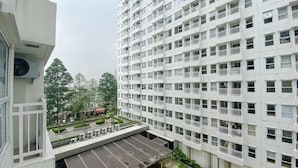 A multi-story residential building with balconies, a parking area, and surrounding greenery. - Modern Look Studio Room At Citra Living Apartment (Jakarta)