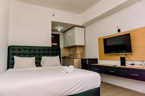 Una habitación de hotel moderna con una cama grande, un televisor de pantalla plana en la pared y un escritorio de madera con una computadora.