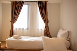 Una habitación de hotel con cama, cortinas y ventana.