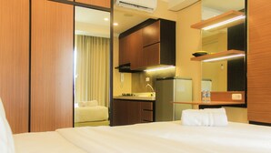 Ein Hotelzimmer mit Bett, Badezimmer mit Spiegel und einer Küchenzeile mit Herd und Spüle.