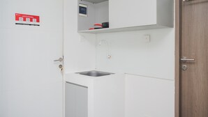 A modern kitchen with white cabinetry, a stainless steel sink, and a small countertop. - Warm And Simply Studio Room At Urbantown Serpong Apartment (South Tangerang)