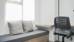 A compact room with a built-in bench, a desk, and a chair. - Warm And Simply Studio Room At Urbantown Serpong Apartment (South Tangerang)