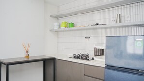 A modern kitchen with a stainless steel refrigerator, a gas stove, and white tiled walls. - Warm And Simply Studio Room At Urbantown Serpong Apartment (South Tangerang)