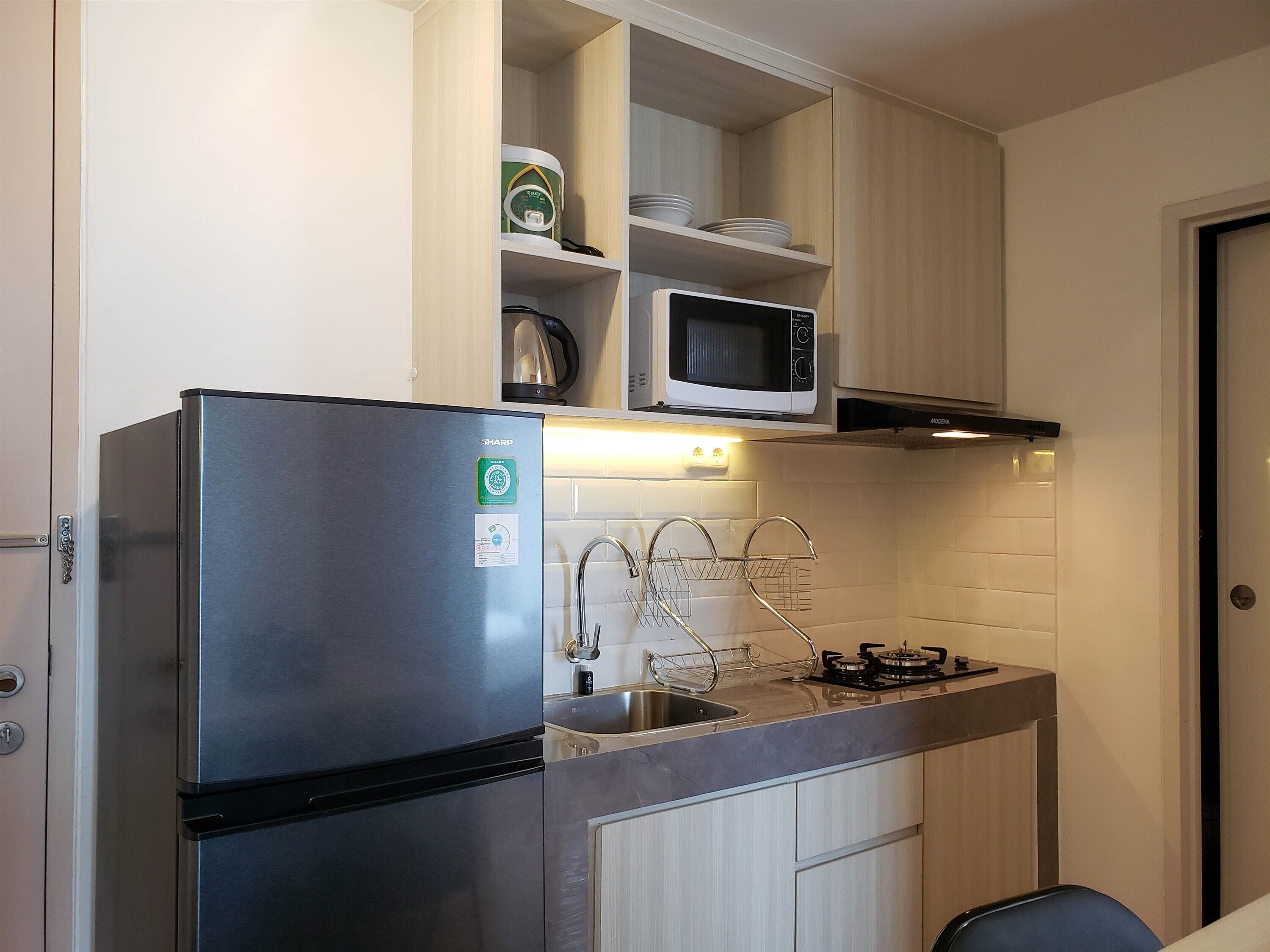 A compact kitchen with a stainless steel refrigerator, a microwave, and a gas stove.
