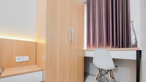 Ein Zimmer mit einem Holzschrank, einem Schreibtisch mit Stuhl und einem Vorhang.