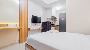 Ein modernes Hotelzimmer mit Bett, Fernseher, Schreibtisch und Duschbereich.