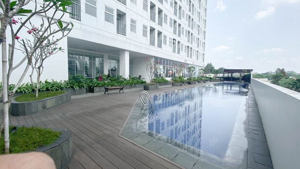 Ein modernes Hotel mit Pool auf dem Dach, Außenbereich zum Sitzen und üppiger Bepflanzung.