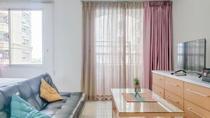 Een moderne woonkamer met een leren bank, een glazen salontafel en een televisie op een standaard.