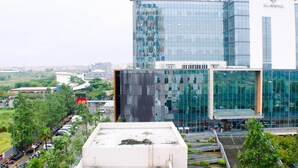 A modern hospital building with a glass facade and a parking area in front. - Nice And Homey Studio At Sayana Bekasi Apartment (Bekasi)