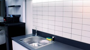 A modern kitchen with a stainless steel sink, black cabinets, and white tiled backsplash. - Nice And Homey Studio At Sayana Bekasi Apartment (Bekasi)