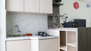 A compact kitchen with a sink, stove, and dish rack. - Stunning And Comfy 2Br Bassura City Apartment (Jakarta)