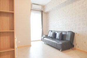 Una sala moderna con un sofá gris, estanterías de madera y papel tapiz estampado.