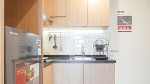 Eine Küche mit Holzausstattung, einem Edelstahlkühlschrank, einer Spüle und einem Küchenutensilienhalter.