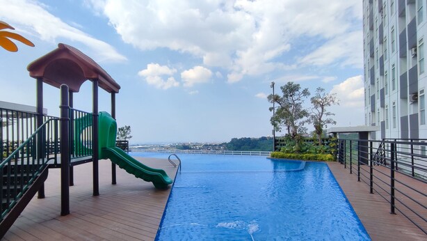 Une piscine sur le toit, avec un toboggan vert et une vue sur le paysage urbain.