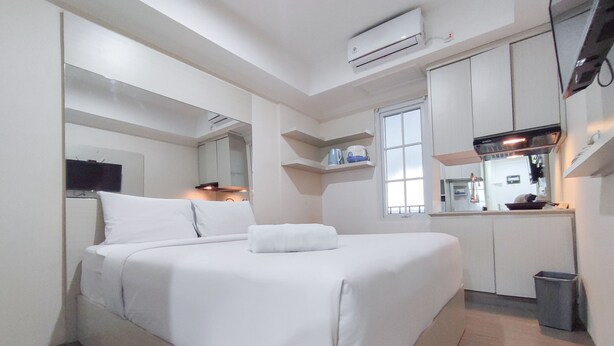 Moderni hotellihuone, jossa on suuri sänky, pieni keittonurkkaus ja kylpyhuone.