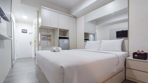 Hotellihuone, jossa on suuri sänky, vaatekaappi, televisio ja minibaari.