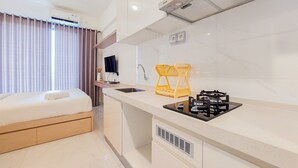 A modern hotel room with a bed, a kitchenette, and a bathroom. - Comfy Studio Room At 31St Floor Sky House Bsd Apartment (Pagedangan)