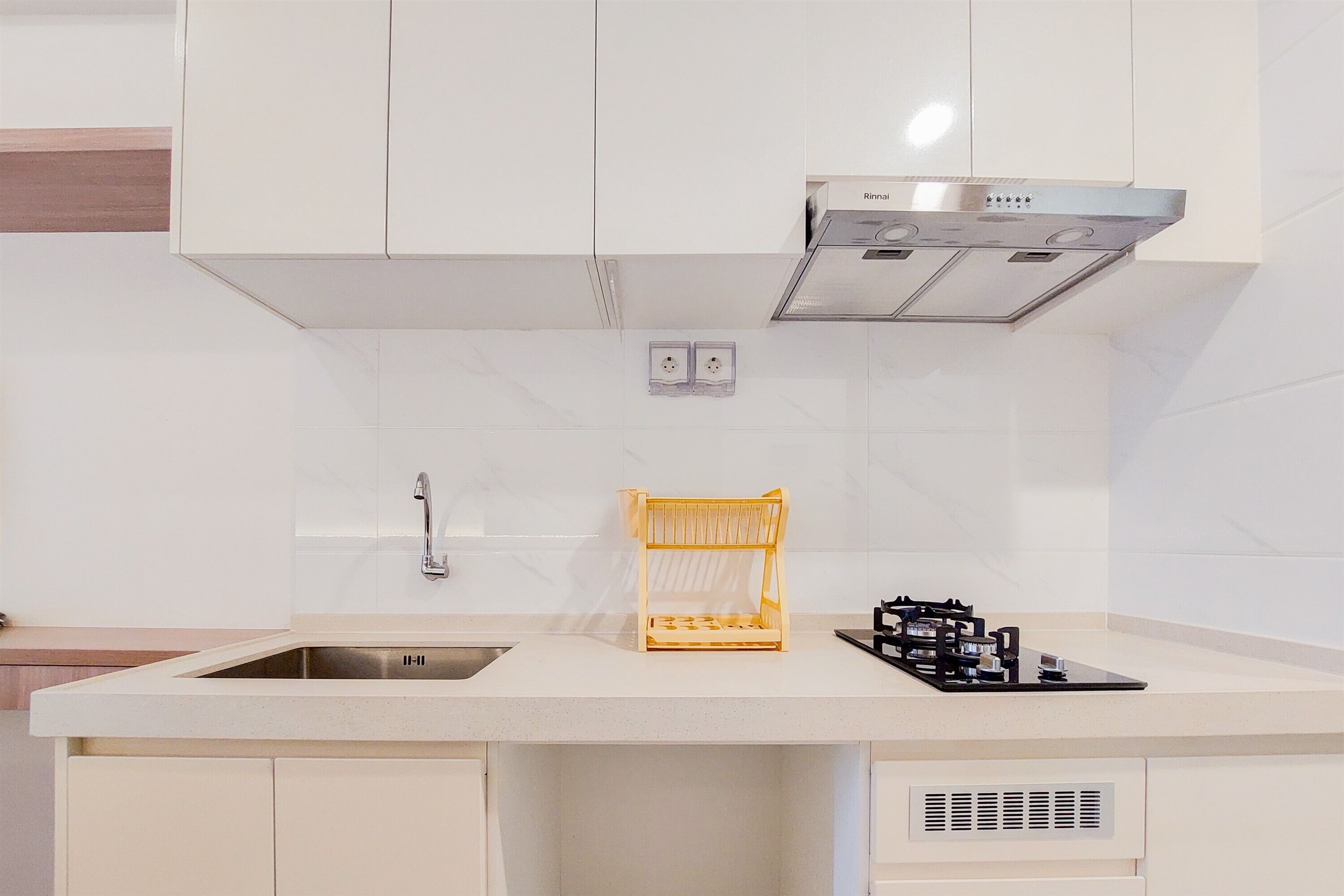 A kitchen with white cabinets, a stainless steel sink, a wooden rack, and a gas stove.