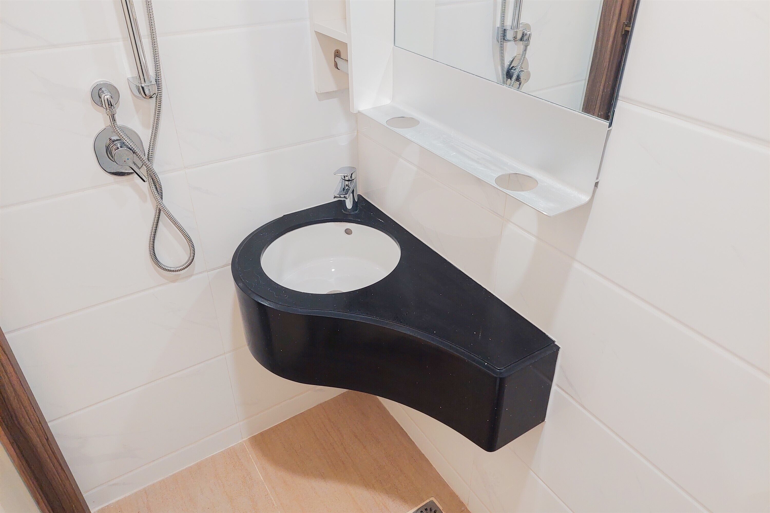A bathroom with a black sink, white tiles, a mirror, and a shower head.