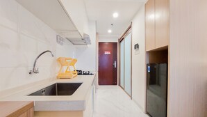 A modern kitchen with a sink, stove, and refrigerator. - Comfy Studio Room At 31St Floor Sky House Bsd Apartment (Pagedangan)