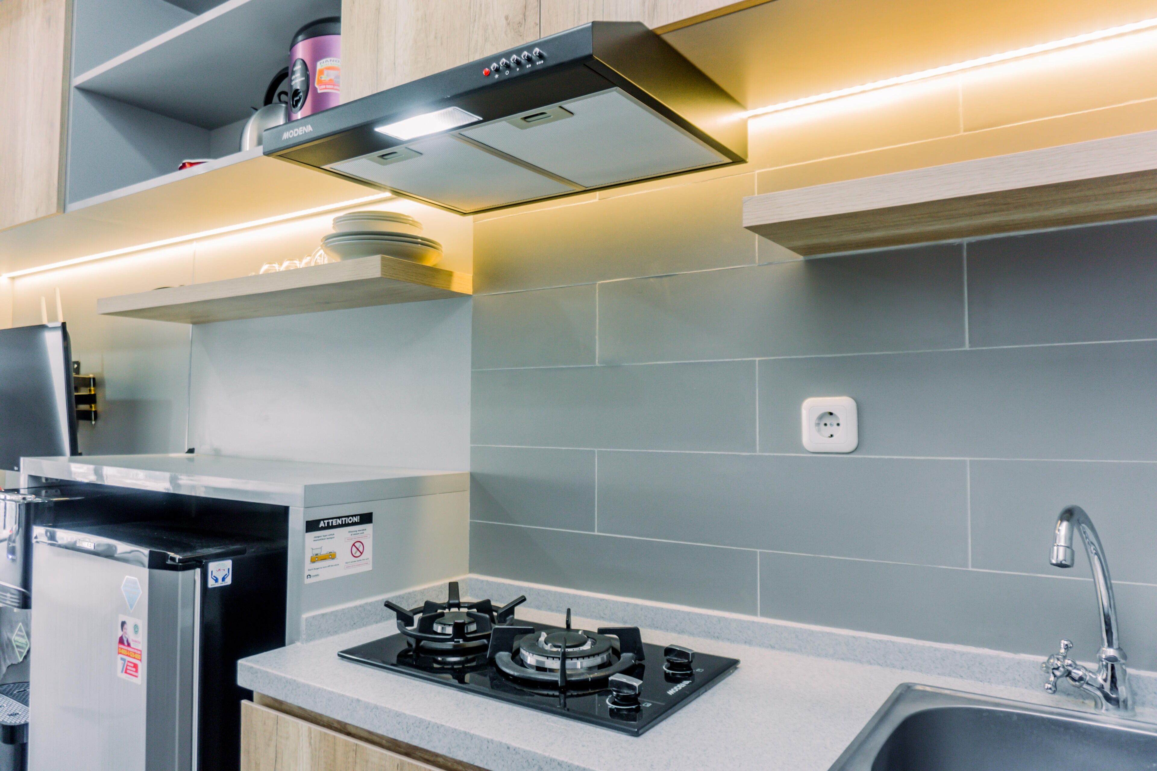 Una cocina moderna con estufa a gas integrada, electrodomésticos de acero inoxidable y salpicadero de azulejos grises.