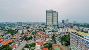 A high-rise building with a modern design, surrounded by a densely populated urban area with various buildings and greenery. - Relaxing Studio Apartment At Margonda Residence 2 Near Ui (Depok)