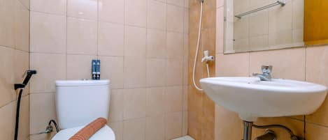 A bathroom with a toilet, a shower, and a sink.