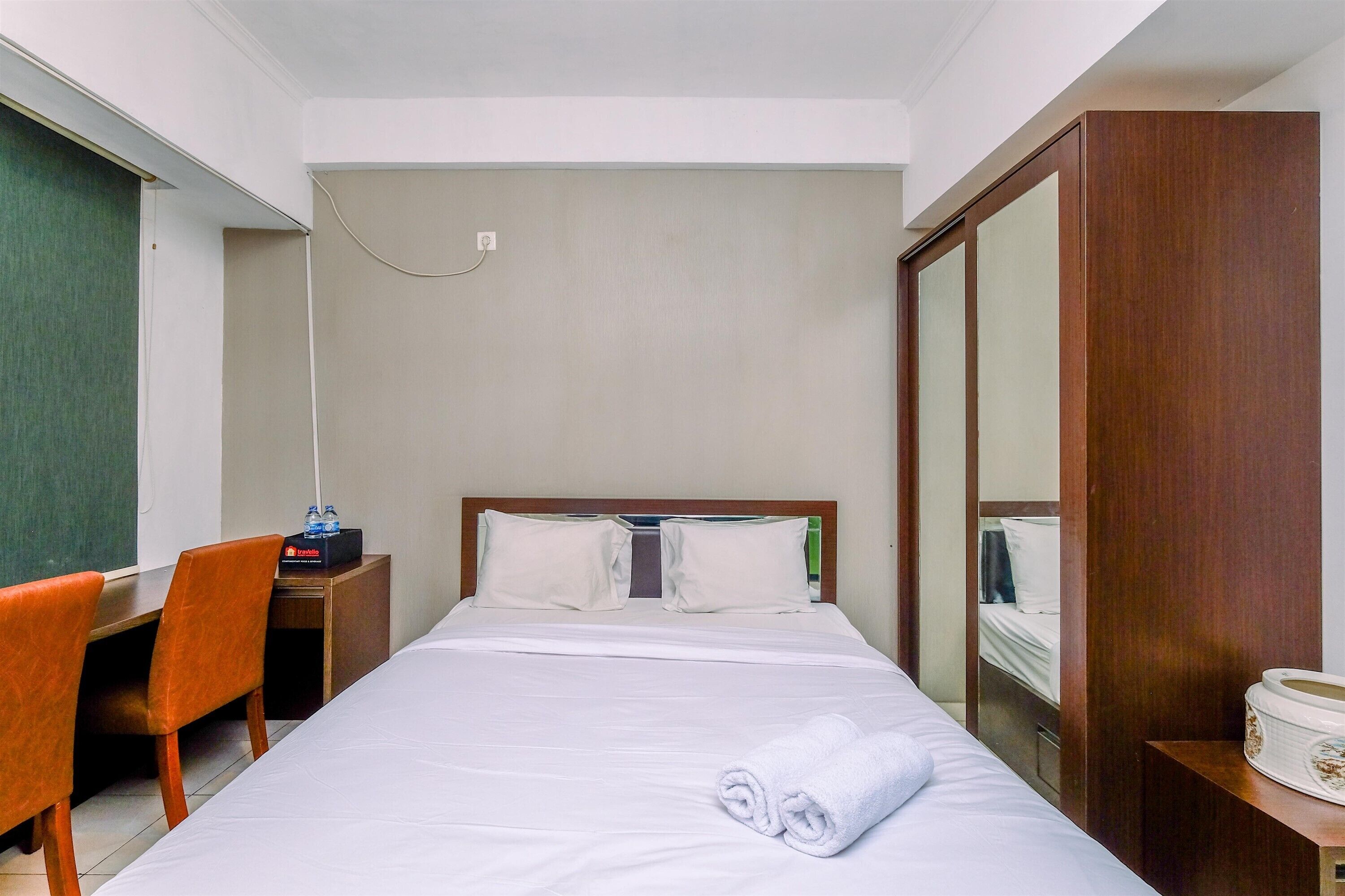 Una habitación de hotel con una cama, un escritorio, una silla y un espejo.